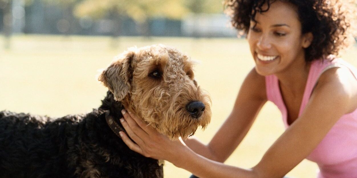 A woman happily petting a friendly dog outdoors.